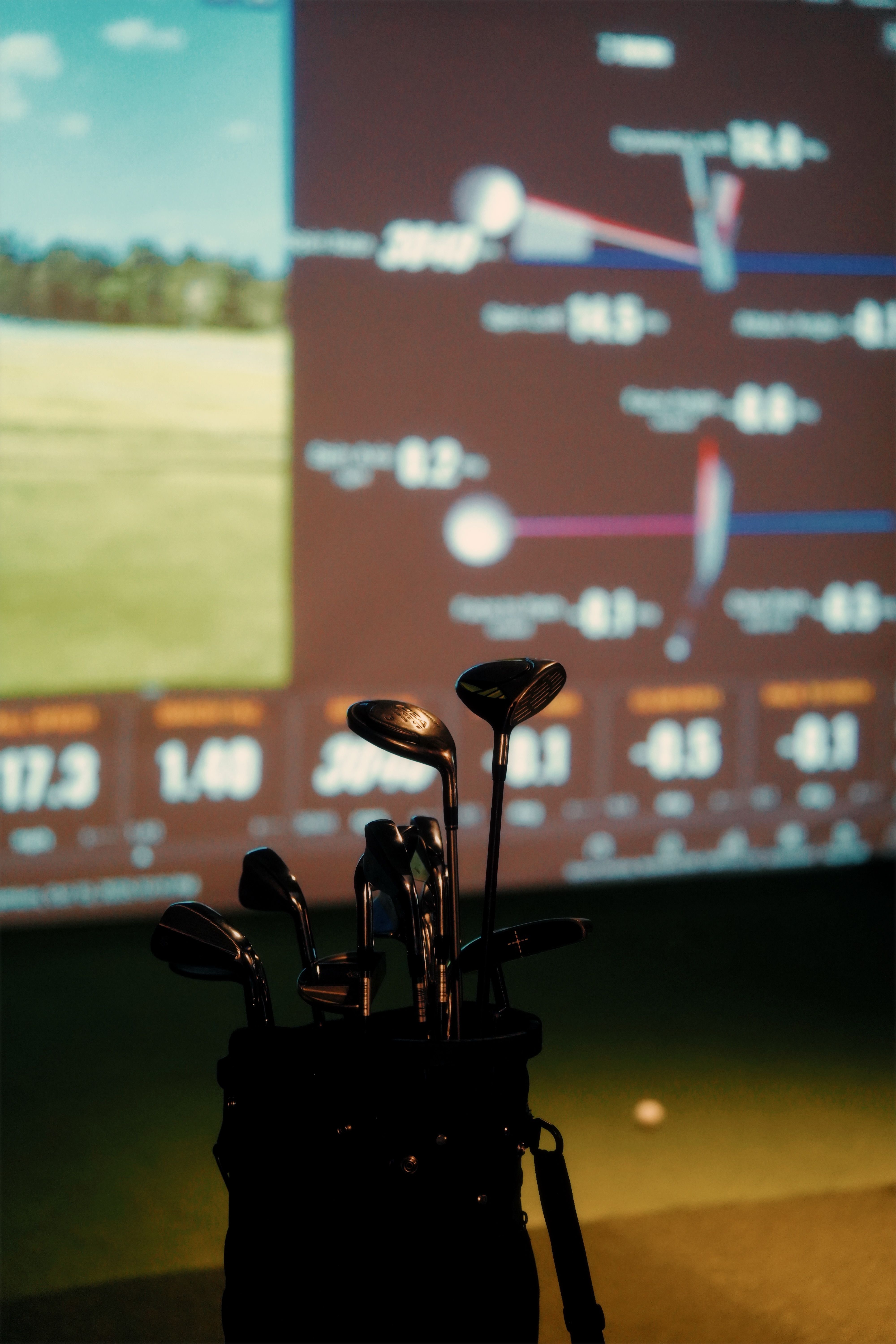 A close view of shot-data figures on a screen with a rack of club heads in the foreground.