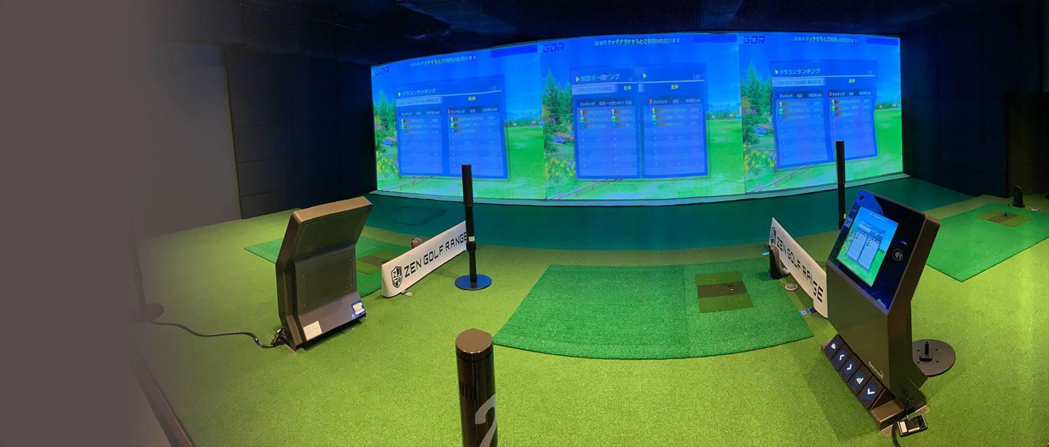 A row of simulator booths with fairway screens, hitting mats and touch-screen consoles on green turf.
